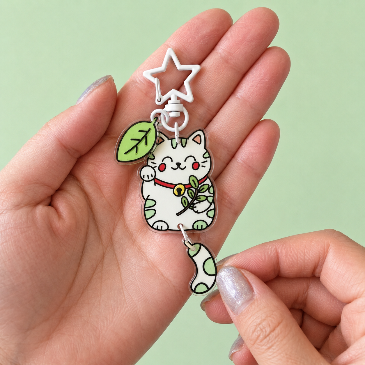 Porte-clé Maneki Neko vert avec queue articulée tenu entre deux mains